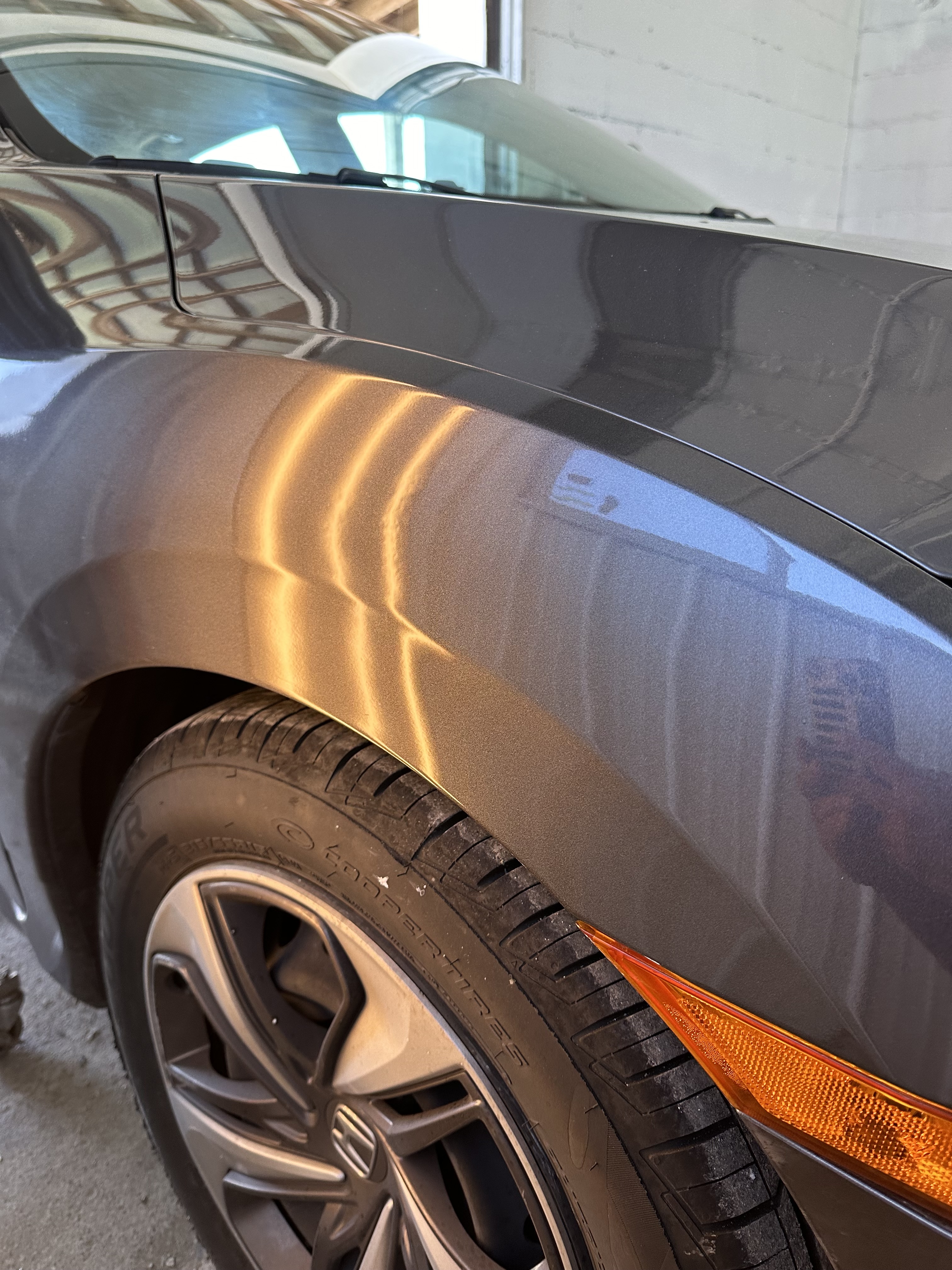 Same car fender restored to smooth factory finish after PDR repair